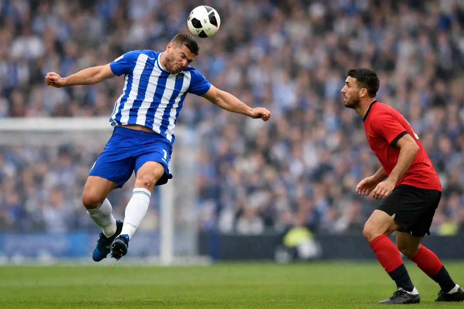 Football defender making a decisive clearance with the ball in the air